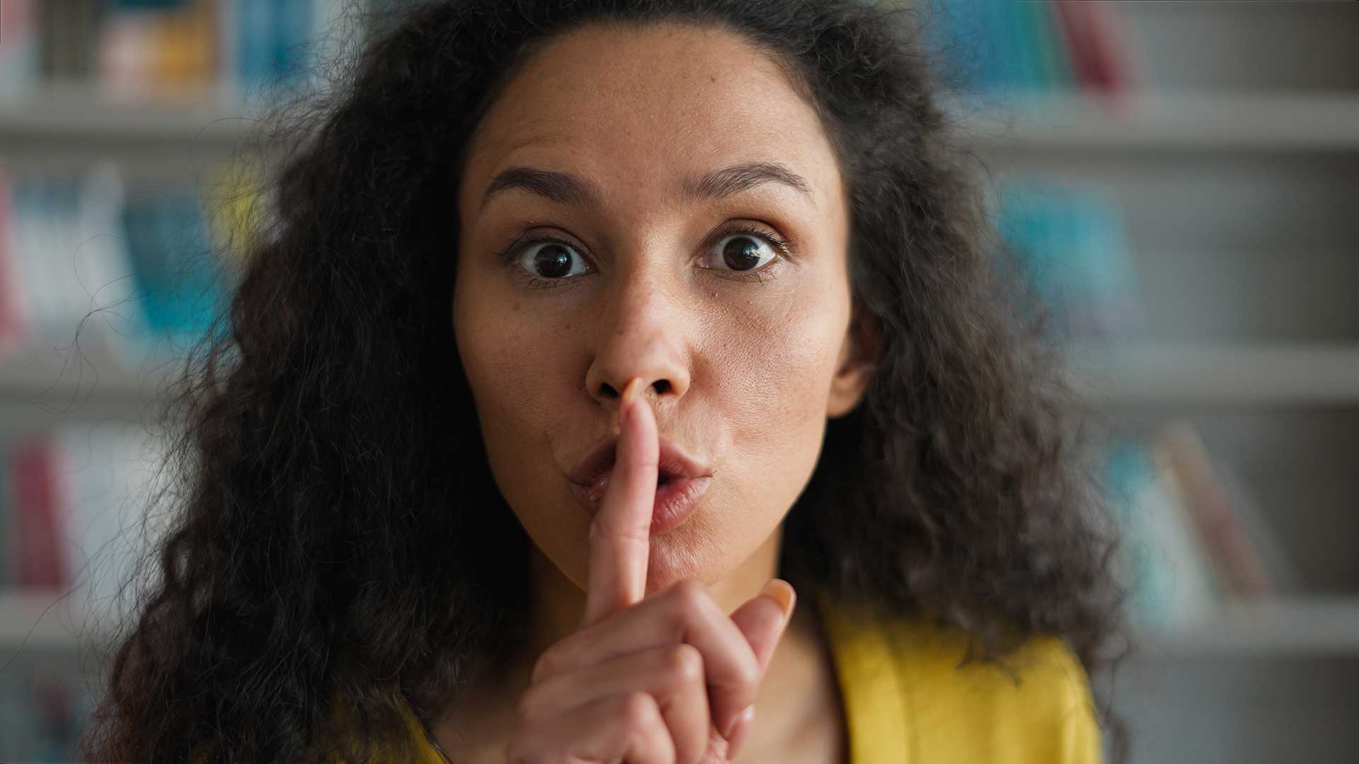 woman saying shhh with finger in front of mouth.