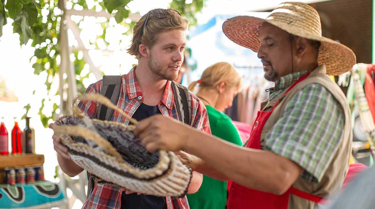 Market trader selling bag to tourist.