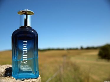 Bottle of Tommy Hilfigure cologne with open field in the background.